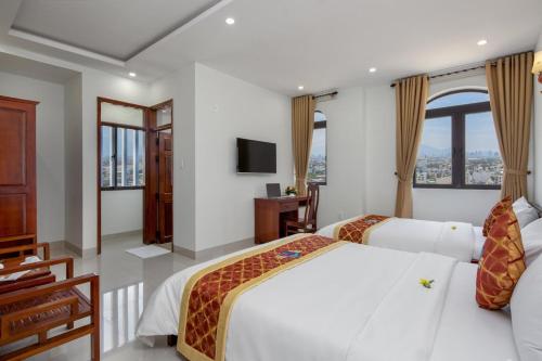 a hotel room with two beds and a television at Khách sạn Phạm Gia Đà Nẵng (Phạm Gia Hotel) in Da Nang