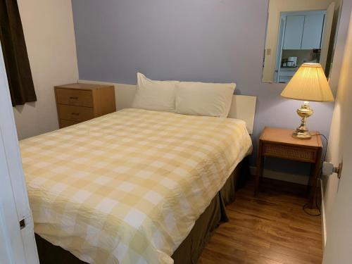 a small bedroom with a bed and a lamp on a table at Swiss Sunset Inn in Penticton