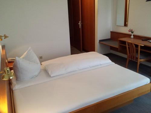 1 cama con sábanas blancas y almohadas en una habitación en Hotel am Exerzierplatz, en Mannheim