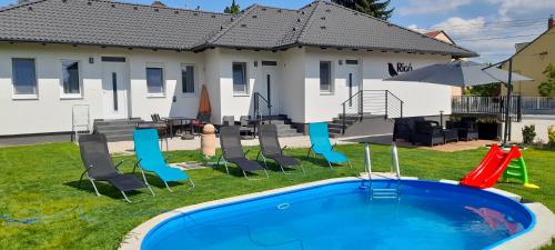 un patio trasero con piscina y sillas y una casa en Rigó Apartman, en Keszthely