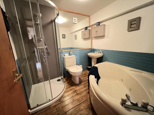 a bathroom with a tub and a toilet and a sink at Tall Ship - Three-bedroom coastal house with sea views in Anstruther