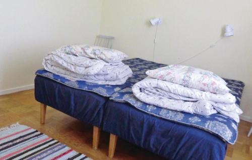 łóżko z stosem koców i poduszek w obiekcie Stunning Home In Frjestaden With Kitchen w mieście Färjestaden