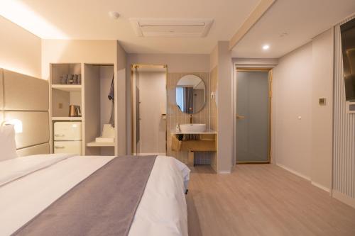 a bedroom with a bed and a bathroom with a sink at Denbasta Central Hotel Seomyeon in Busan