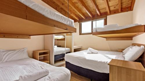two beds in a room with two bunk beds at Razorback 7 in Mount Hotham