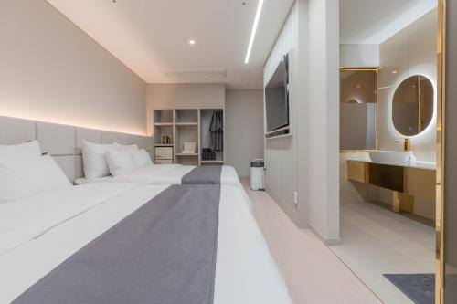 a bedroom with a large white bed and a sink at Denbasta Central Hotel Seomyeon in Busan