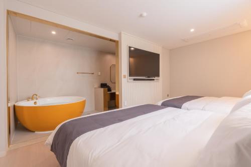 a bedroom with a large bed and a bath tub at Denbasta Central Hotel Seomyeon in Busan