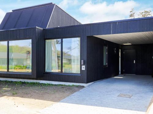 a black house with a large glass door at 6 person holiday home in Gilleleje-By Traum in Gilleleje
