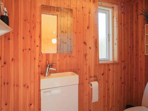 een badkamer met houten wanden, een wastafel en een spiegel bij Holiday home Gilleleje LXXXVII in Gilleleje