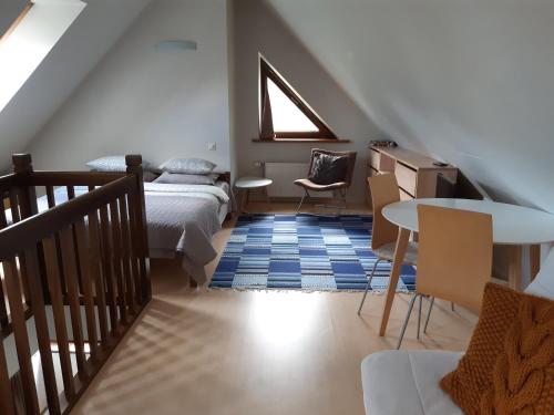 1 dormitorio en el ático con 1 cama, mesa y sillas en Lazdas en Saulkrasti
