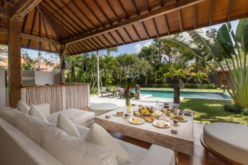 een woonkamer met witte banken en een tafel met eten bij The Radian Villa in Canggu