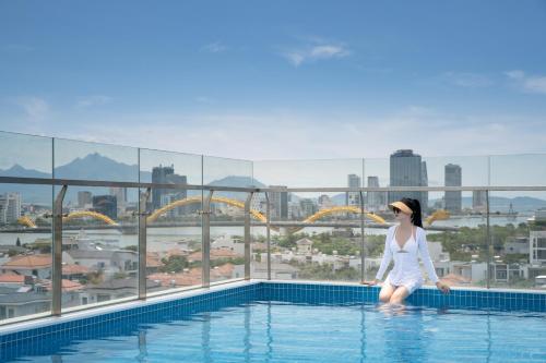 a woman standing on the edge of a swimming pool at Santori Hotel And Spa in Da Nang