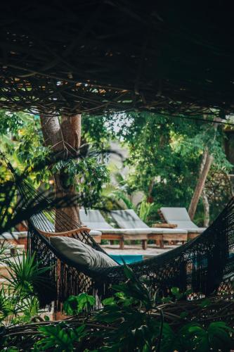 a hammock in front of a resort with a pool at Kan Tulum Hotel in Tulum