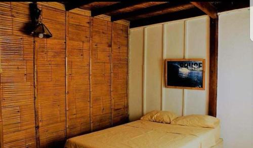 ein Schlafzimmer mit einem Bett und einer Holzwand in der Unterkunft Aylluwasihostel in Máncora