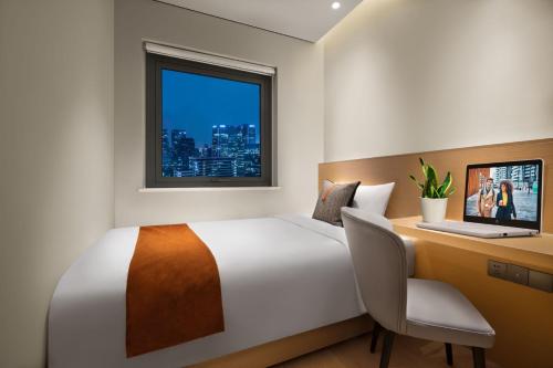 een slaapkamer met een bed, een bureau en een raam bij Citadines Gaoxin Chengdu in Chengdu