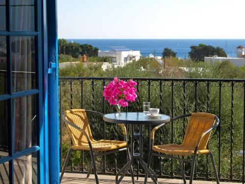 a table with two chairs and a vase of flowers on a balcony at Castellania Hotel Apartments in Livadia