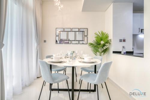 a white dining room with a white table and chairs at Cheerful 3BR Townhouse at DAMAC Hills 2, Dubailand by Deluxe Holiday Homes in Dubai