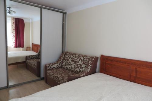 a bedroom with a bed and a chair and a mirror at WILLOW apartamenti in Liepāja