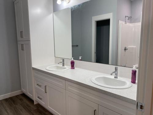 ein Badezimmer mit zwei Waschbecken und einem großen Spiegel in der Unterkunft Thistle Ridge (Lower) New Waterton Lakes Area Waterfront Home in Mountain View