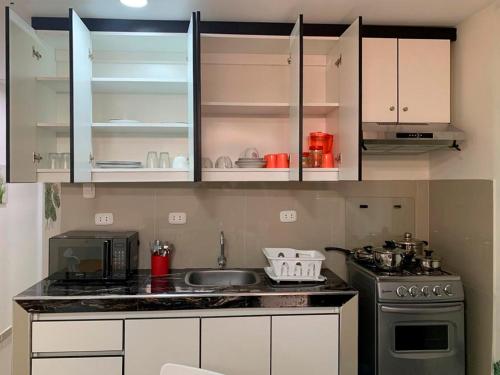 a kitchen with a sink and a stove and cabinets at Acogedor departamento amoblado en san miguel, primer piso, wifi. in Lima