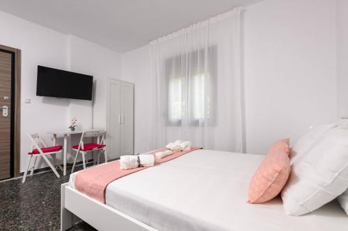 a white bedroom with a large bed with pink pillows at Whitegold Apartments Panagia in Panayia