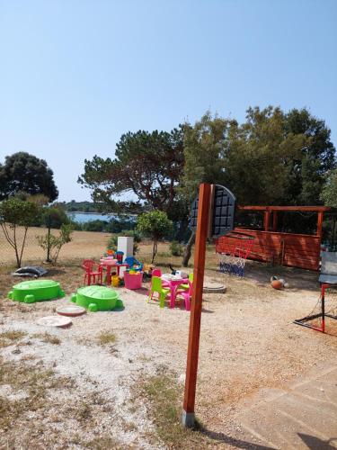 un parque infantil con sillas y mesas coloridas y un poste en Grand Veles camp, en Pula