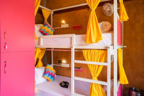 a room with two bunk beds with yellow curtains at goSTOPS Pondicherry Near Auroville in Auroville