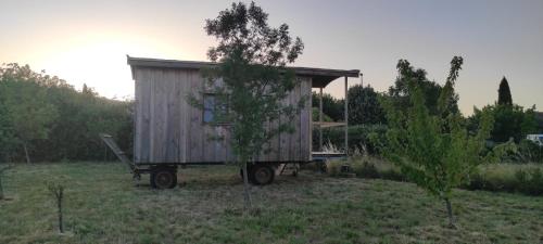 a tiny house sitting on a trailer in a field at La roulotte de Nico in Alba La Romaine