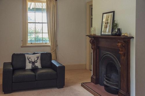 a living room with a chair and a fireplace at CLAYFIELD HOMESTEAD - rustic country accommodation in Bishopsbourne