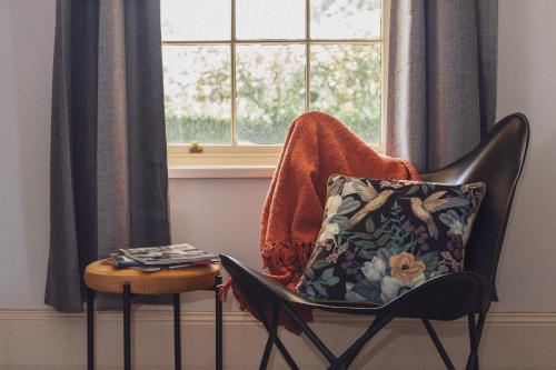 a chair with a pillow on it next to a window at CLAYFIELD HOMESTEAD - rustic country accommodation in Bishopsbourne