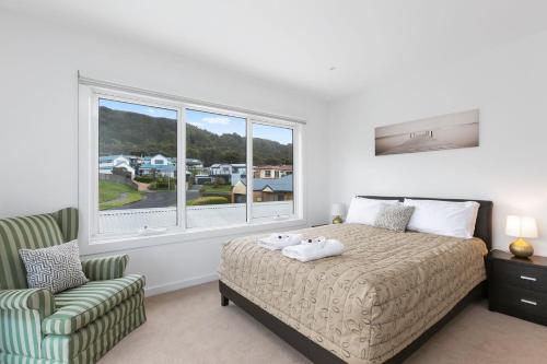 una camera da letto con un letto, una sedia e una finestra di Seaview Apollo Escape - BYO Linen a Apollo Bay