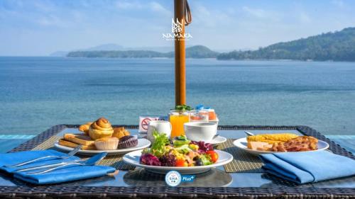 ein Frühstückstisch mit Essen und Blick auf das Meer in der Unterkunft Namaka Resort Kamala in Kamala Beach