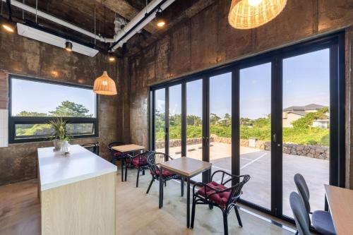 a dining room with tables and chairs and large windows at Liverpool & Spa in Jeju