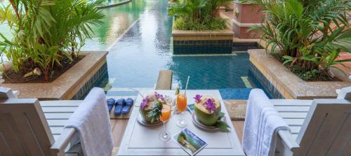 a table with a plate of food next to a swimming pool at Ayodhaya Palace Beach Resort-Family run -SHA Plus certified in Ao Nang Beach