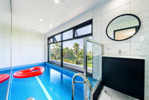 a bathroom with a swimming pool and a red stool at Liverpool & Spa in Jeju