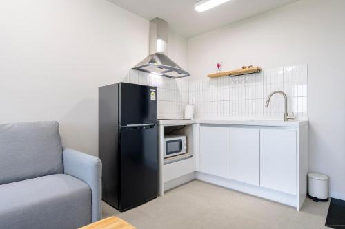 a small kitchen with a black refrigerator and a sink at Liverpool & Spa in Jeju