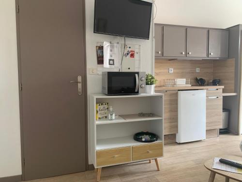 La cuisine est équipée d'un réfrigérateur blanc et d'un four micro-ondes. dans l'établissement PYRENE HOLIDAYS - Résidence La Fontaine - Studios cozy à 10mn à pied des thermes, à Bagnères-de-Bigorre