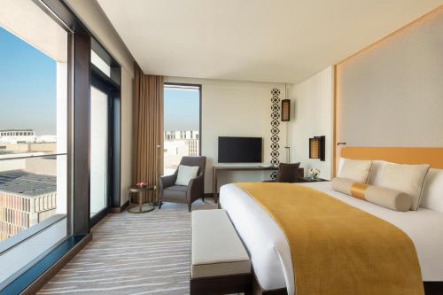 a hotel room with a bed and a large window at Alwadi Hotel Doha - MGallery Collection in Doha