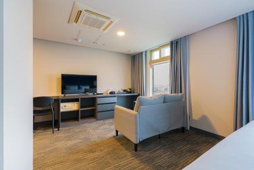 um quarto de hotel com uma cadeira e uma televisão em Little Prince Hotel em Gunsan