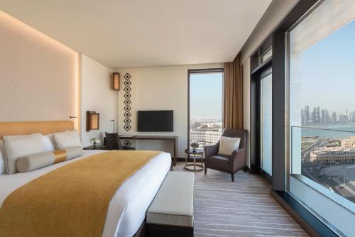 a hotel room with a bed and a large window at Alwadi Hotel Doha - MGallery Collection in Doha