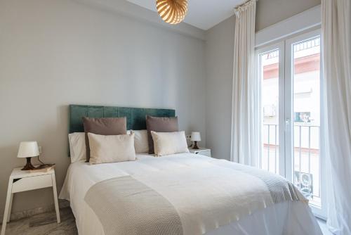 biała sypialnia z dużym łóżkiem i oknem w obiekcie Guadalquivir Terrace Suite Apartments w Sewilli