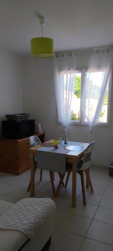 einen Tisch und Stühle im Wohnzimmer mit Fenster in der Unterkunft Montignac lascaux chambre in Montignac