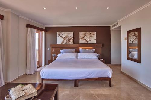 a bedroom with a large bed and a table at Maristel Hotel & Spa - Adults Only in Estellencs