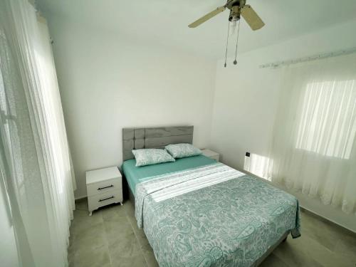 a bedroom with a bed and a ceiling fan at Bodrum Gündoğan Koyu Havuzlu Site in Bodrum City