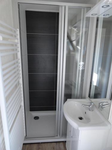 a white bathroom with a shower and a sink at Stellechalets op Vakantiepark Stelleplas - Heinkenszand in Heinkensand