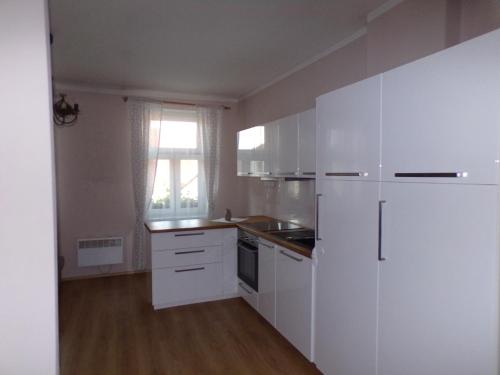a white kitchen with white appliances and a window at Penzion Restaurace u Helferů in Libuň