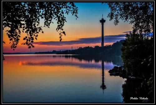 a view of a lake with a water tower in the distance at Lapinniemen kattohuoneistot Tampereella in Tampere