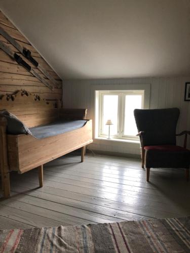 um quarto com uma cama, uma cadeira e uma janela em Vettingstua, beautiful house down by the sea. em Gravdal