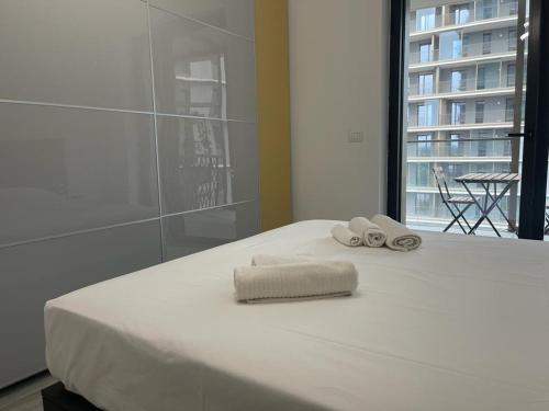un letto bianco con due asciugamani sopra di Kibilù - Cascina Merlata Rho Fiera Ospedale Galeazzi a Pero