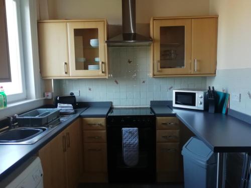 a kitchen with a sink and a microwave at Carvetii - Walter House - First floor flat sleeps 6 in Leslie
