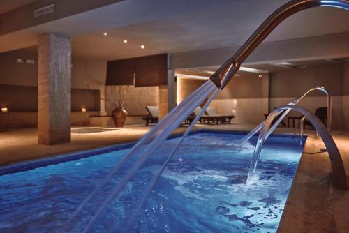 una piscina en una habitación de hotel con una fuente de agua en Maristel Hotel & Spa - Adults Only, en Estellencs